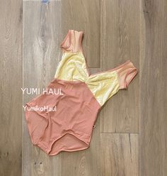 a woman's swimsuit laying on the floor in front of a wooden floor