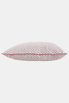 a white and red pillow sitting on top of a bed