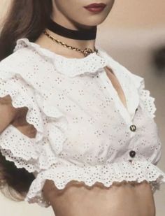 a woman wearing a white shirt and black choker with her hands on her hips