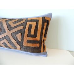 a brown and black pillow sitting on top of a white table next to a wall