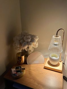 a wooden table topped with a lamp next to a vase filled with flowers