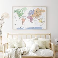 a bed with pillows and a map on the wall above it in a white room