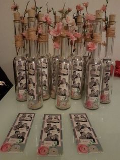 there are many bottles with pictures in them on the table next to each other and some pink flowers