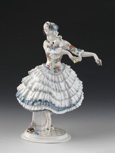 Figurine of the character Chiarina in the ballet Le Carnaval choreographed by Mikhail Fokine with music by Robert Schumann and designs by Léon Bakst, created in 1910 for Serge Diaghilev's Ballets Russes. Figure modelled by Paul Scheurich (1883-1945) for Meissen, 1914. Porcelain. Robert Schumann, Ballets Russes, Porcelain Figures, Blue And Purple Flowers, The Ballet, White Caps, Figure Model