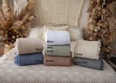 four different colors of towels stacked on top of each other in front of a chair