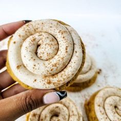 a person is holding a cinnamon roll in their left hand and there are other pastries on the table