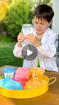 a young boy holding a wine glass in front of some stuffed animals on a table