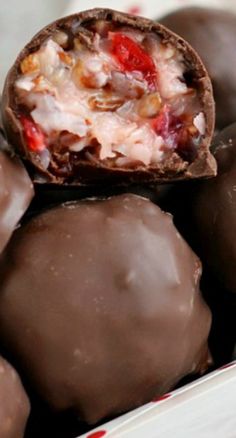 some chocolates are in a white bowl and one is cut open to show the inside