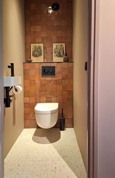 an open door leading to a bathroom with a toilet in the corner and pictures on the wall