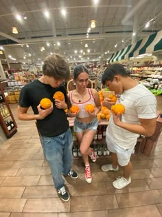 three people are looking at oranges in a store