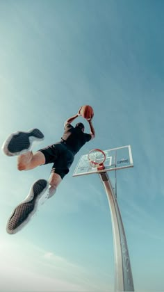 a person jumping up into the air with a basketball in their hand and his feet on a basketball hoop