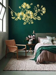 a bedroom with green walls and flowers painted on the wall above the bed, along with a chair