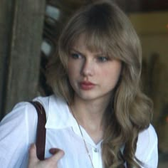 a woman with long blonde hair holding a brown purse