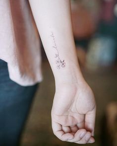 a woman's arm with a small flower tattoo on the left side of her wrist