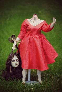 a creepy doll is posed next to a fake woman's head in the grass