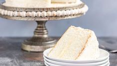 a slice of white cake sitting on top of plates next to a fork and knife