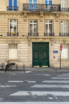 an old building with a green door and bicycle parked on the street in front of it