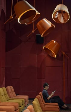 a man sitting on a couch in a room with many lamps hanging from the ceiling