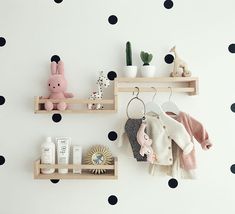 two wooden shelves with baby items on them in front of a polka dot wallpaper