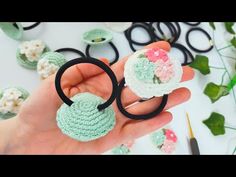 a person is holding some crocheted items in their hand and scissors are on the table