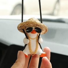 a person holding a small toy penguin wearing sunglasses and a straw hat