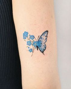 a small blue butterfly tattoo on the right arm and left arm with flowers in it