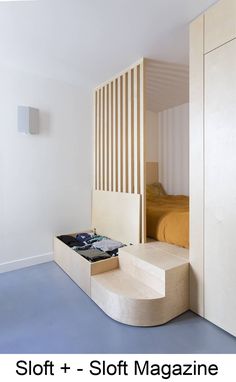 a bed sitting on top of a blue floor next to a wooden wall mounted shelf