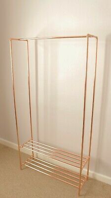 a gold metal rack with two shelves on the wall next to a carpeted floor