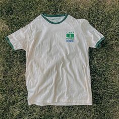 a white t - shirt with green and blue logos on it laying in the grass