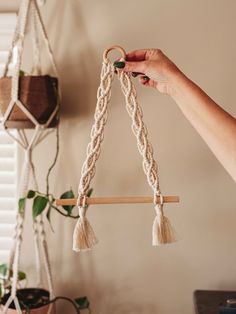 a person is holding up a macrame plant hanger