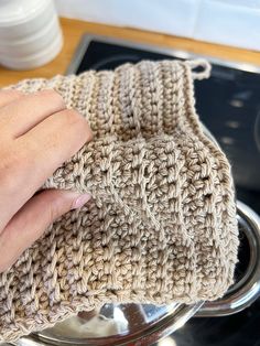 a hand is holding onto a knitted dish cloth