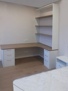 a bedroom with a bed, desk and shelves on the wall next to each other