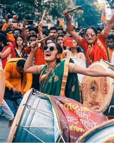 a group of people playing drums and singing in front of a crowd on the street