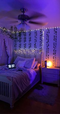 a bedroom decorated with string lights and white bedding in purple lighting up the room