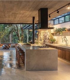 an open kitchen and dining room area with stone walls, floor to ceiling windows, and wooden furniture