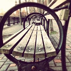 the reflection of a park bench in a circular metal frame that says, i wanna get back to where we are headed