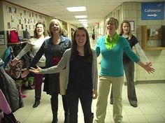 several women are standing in a hallway with their arms out and one woman is holding her hands out