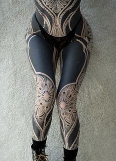 a woman with tattoos on her legs and leggings