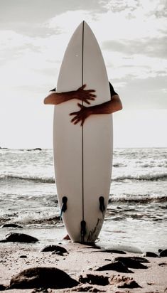 a person holding a surfboard on the beach