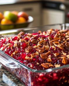 a glass casserole dish filled with cranberry sauce and pecans in the background