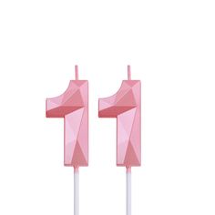 two pink candles with white sticks sticking out of them on a white surface, one is shaped like an origami