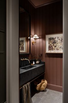 a bathroom sink sitting under a mirror next to a wall mounted light and painting on the wall