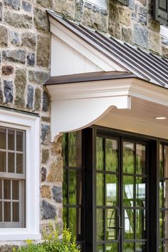 an outside view of a stone building with black doors and windows, including the awning