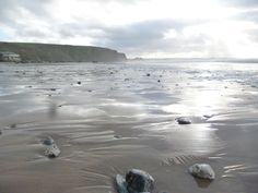 some rocks are laying on the sand by the water's edge, and there is no image here to provide a caption for