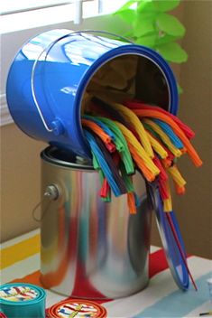 a bucket full of colorful plastic straws sitting on top of a table