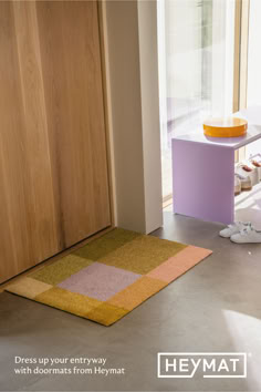 a yellow and pink rug on the floor next to a wooden door in a room