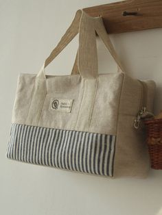 a striped bag hanging on the wall next to a basket and coat rack with hooks