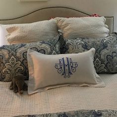 a bed topped with pillows and blankets next to a wall mounted clock in a bedroom