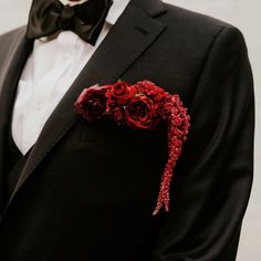 a man in a tuxedo with red flowers on his lapel and bow tie