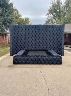 a large black bed sitting in the middle of a driveway